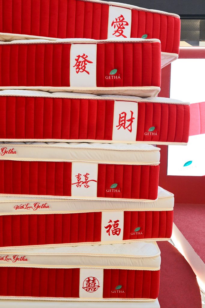 Stack of six mattresses featuring red side panels and various embroidered Chinese characters