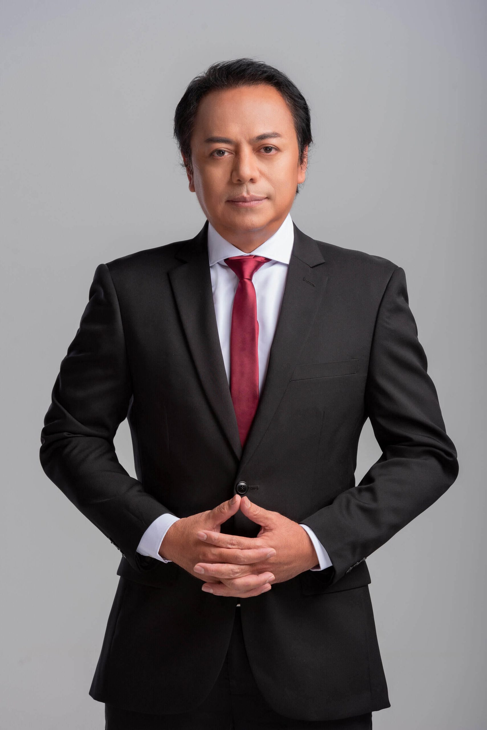 Potret rasmi Pengerusi RIM Rosmin Hashim memakai sut hitam dan tali leher merah berdiri berlatarbelakangkan studio kelabu
