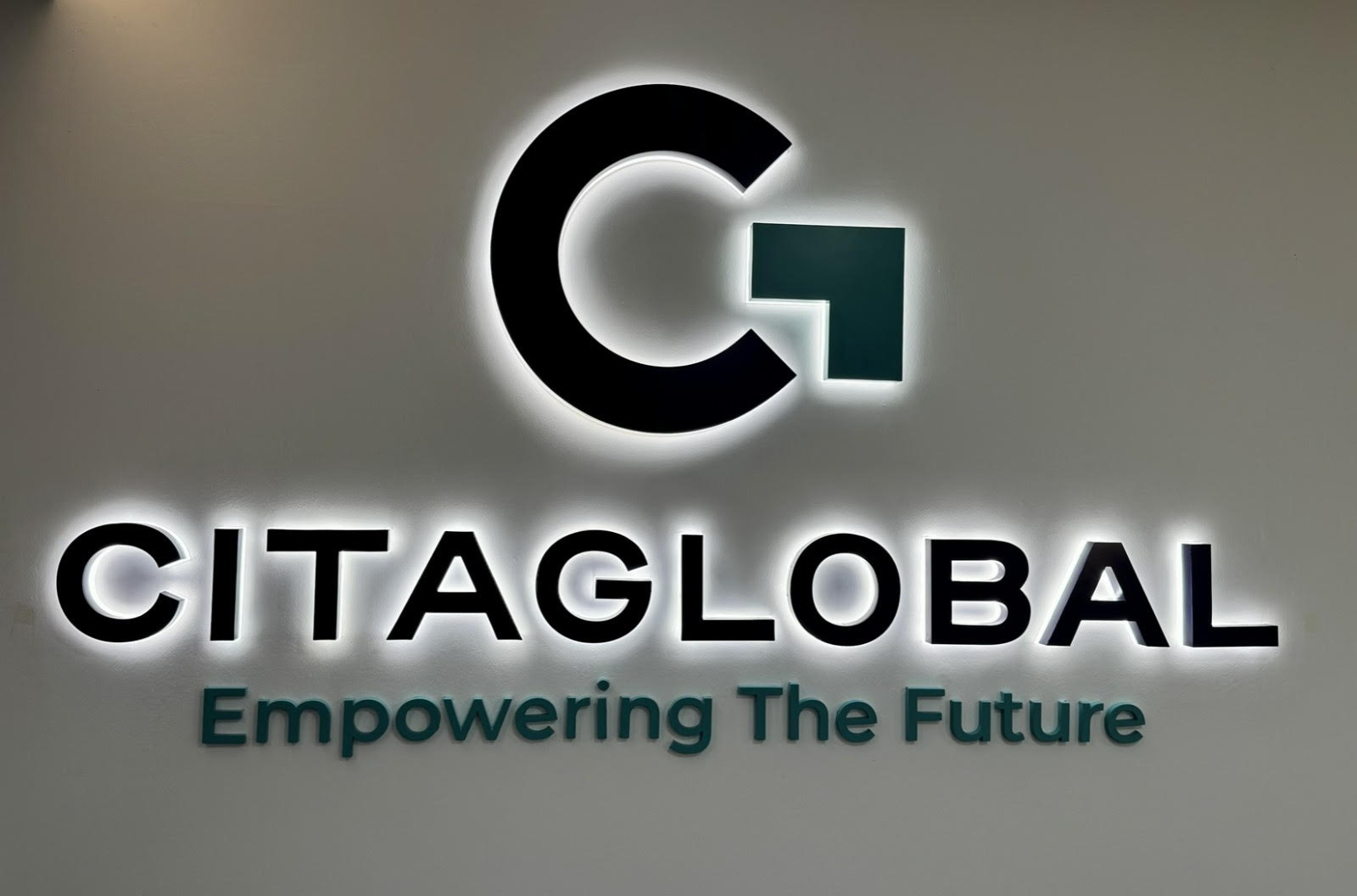 Papan tanda bercahaya logo Citaglobal Berhad dengan slogan Empowering The Future di dinding pejabat korporat